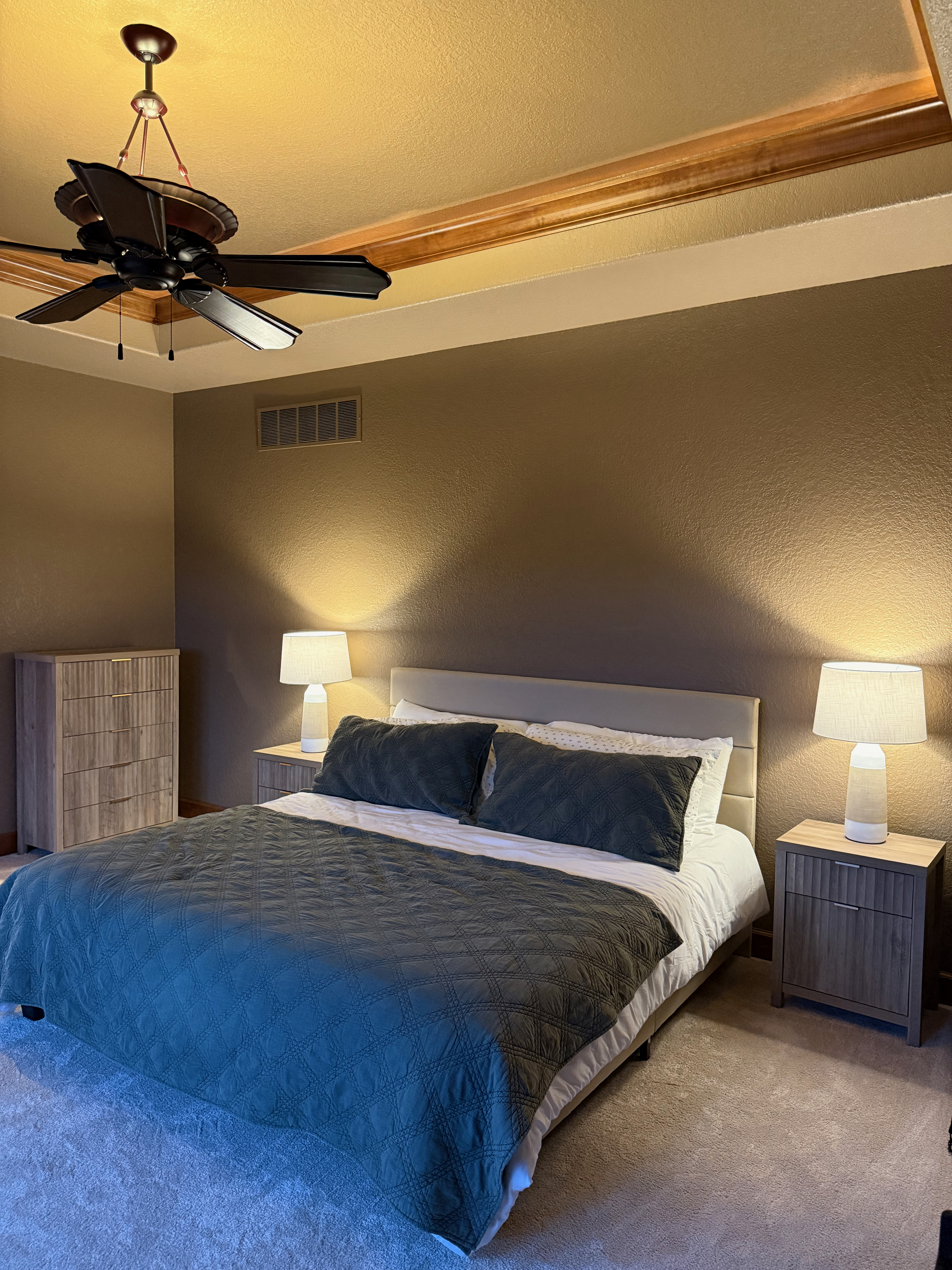 Primary king suite with ceiling fan and tray ceiling