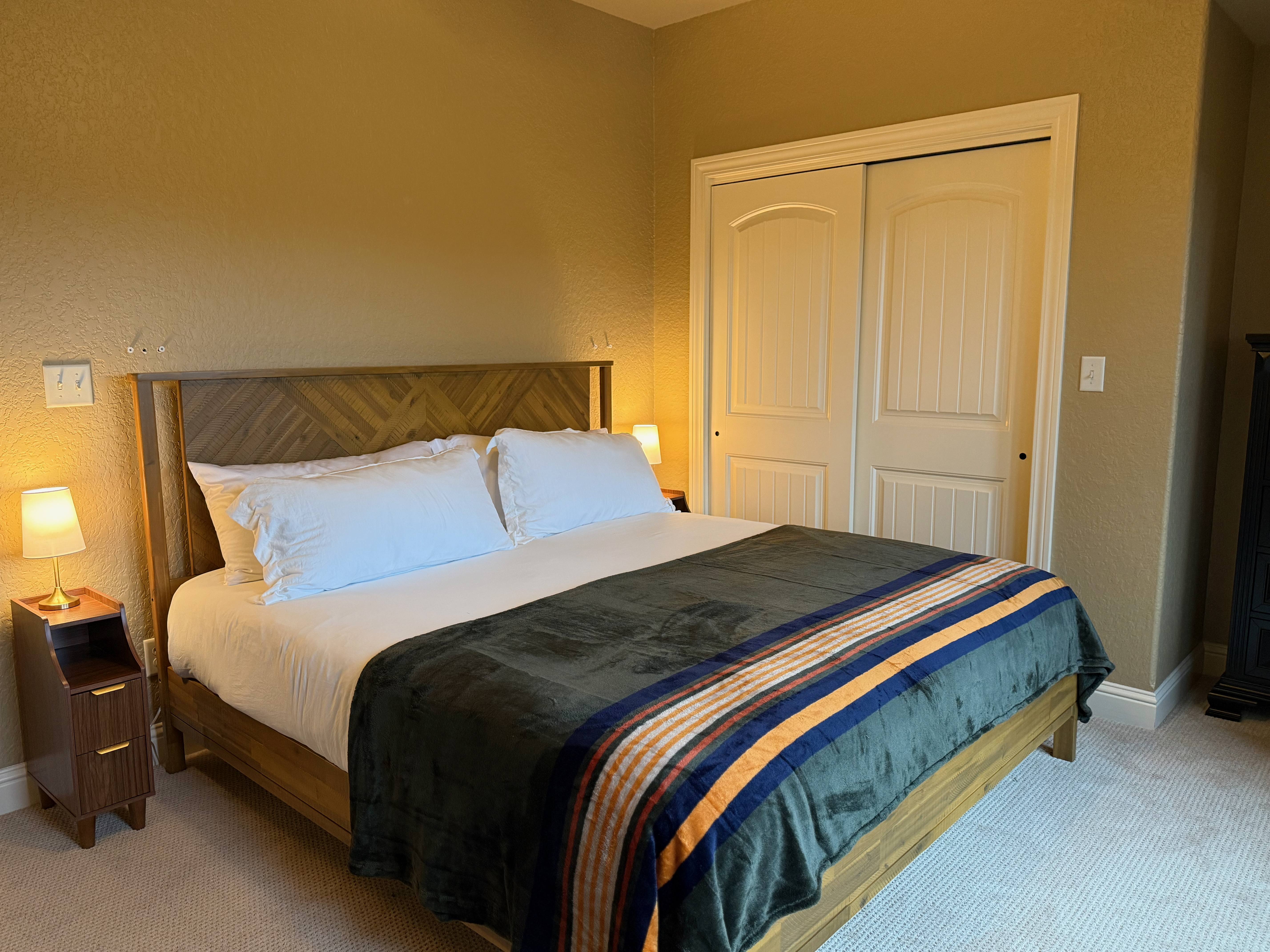 King bedroom with herringbone headboard and striped blanket