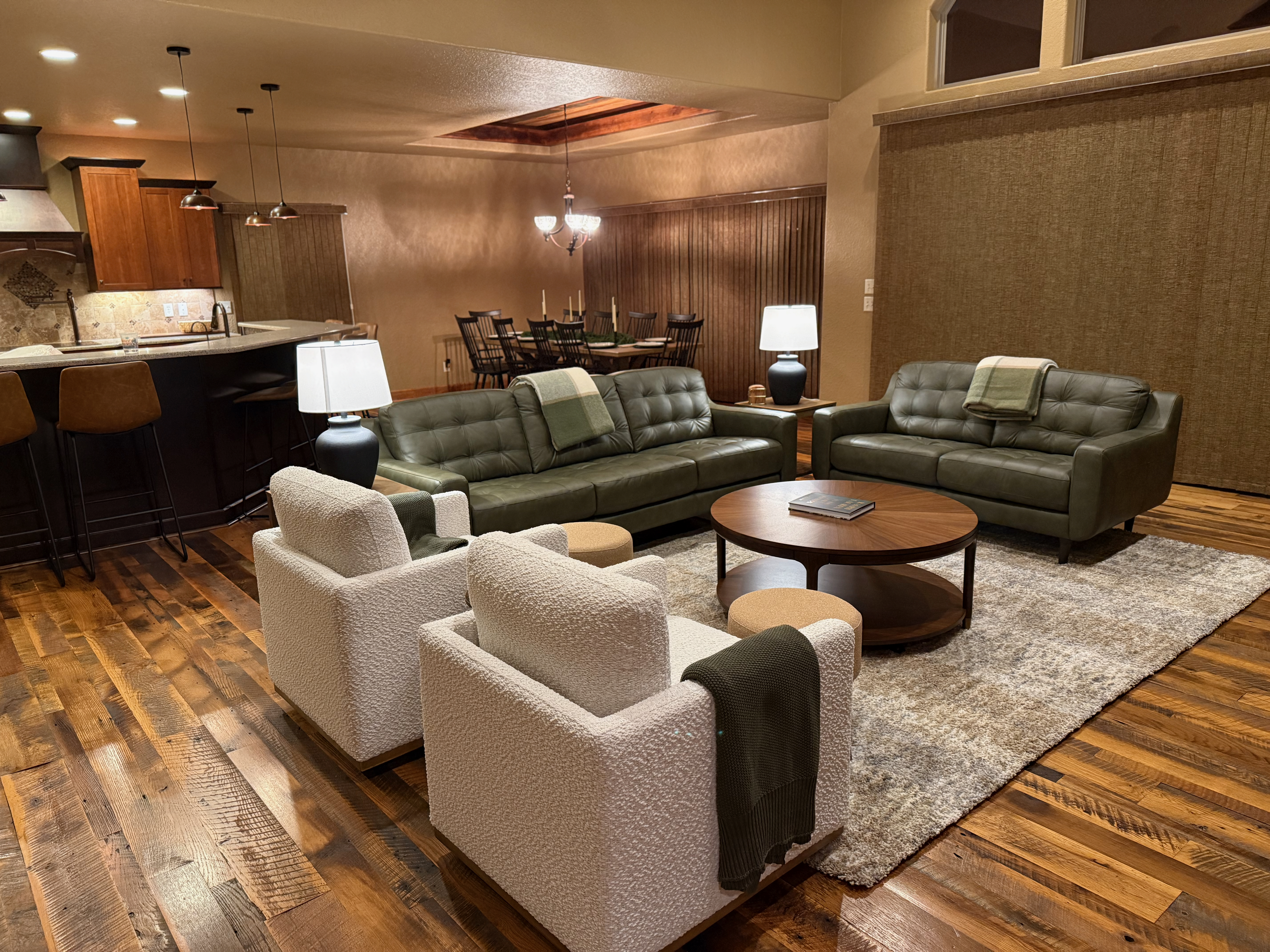 Living room seating area with green sofas and white accent chairs