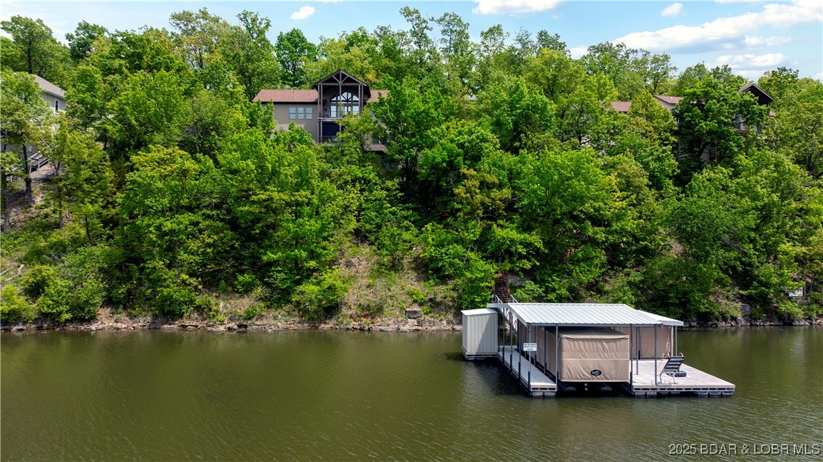 House on wooded hill overlooking the lake with dock